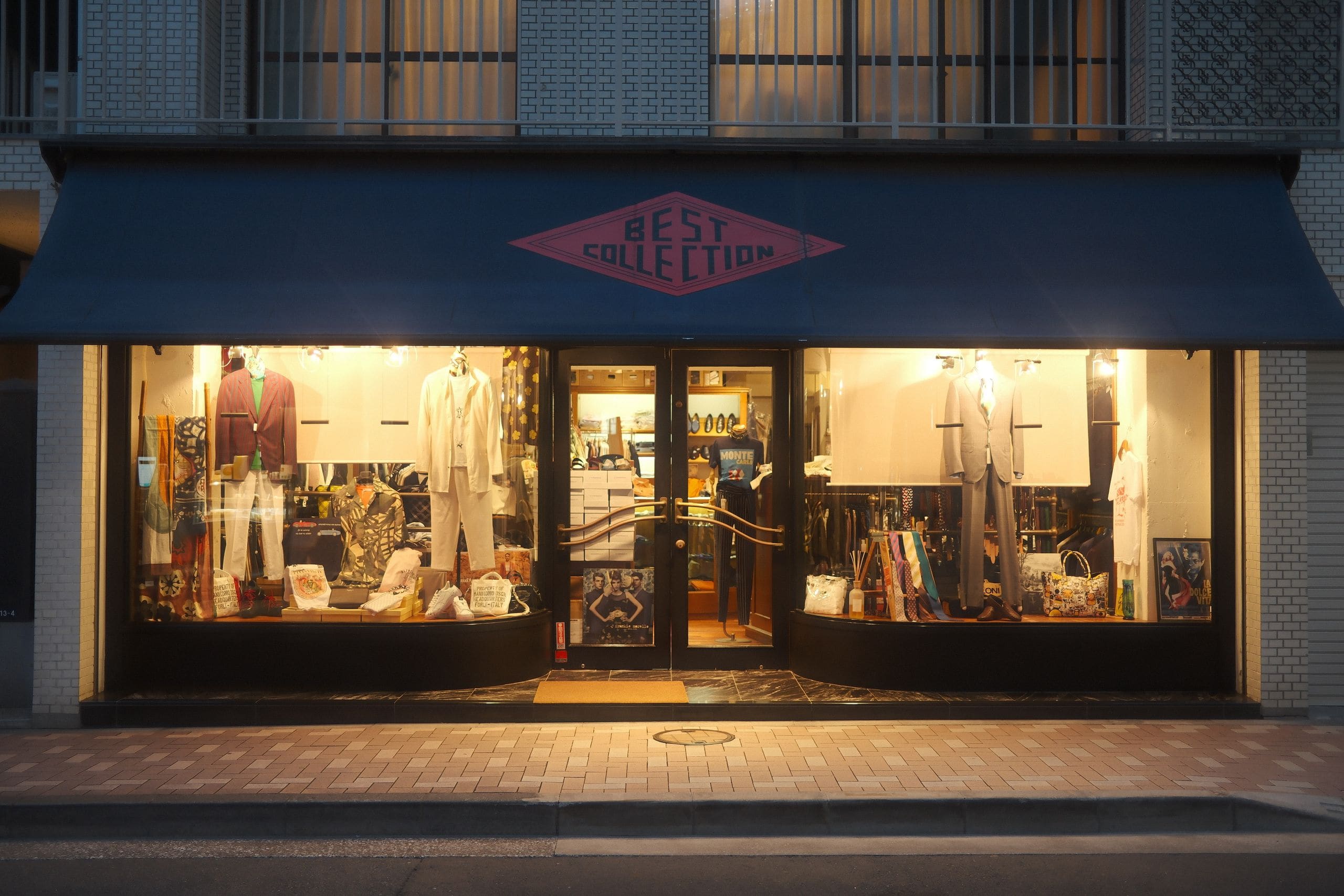 Illuminated flagship storefront at dusk with shoppers passing on the plaza, signage unbranded